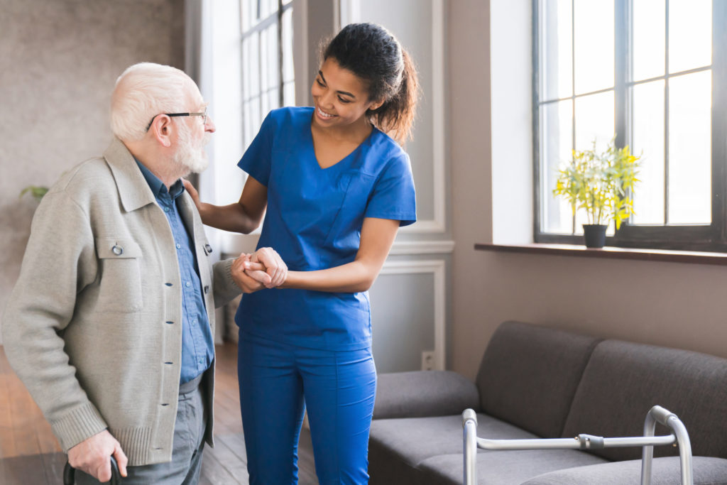 Young CNA assisting elderly man