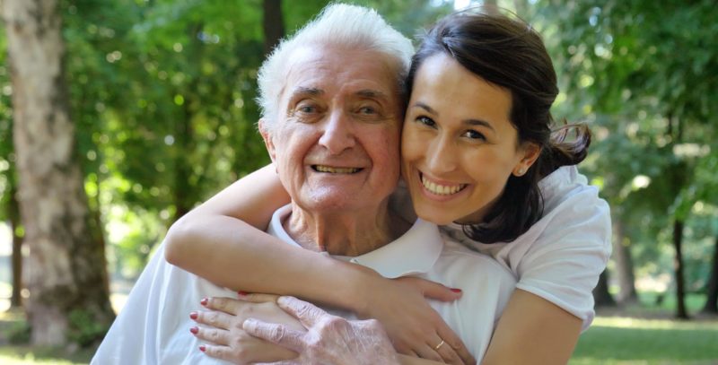 Woman caregiver hugging father