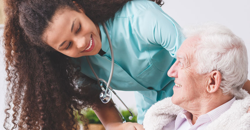 Nurse attends to older adult man in a nursing home.