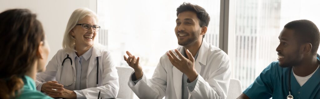 Happy Diverse Medical Team Of Colleagues Talking At Meeting Table