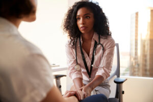 Female Doctor In Office Reassuring Woman Patient And Holding Her Hands