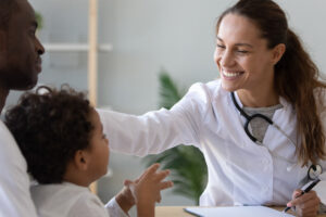 Friendly Female Doctor Stroke Head Of Cute African Child Boy