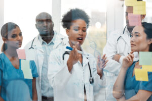 Brainstorming, Presentation And Medical With Black Woman In Meeting For Research, Teamwork And Strategy With Sticky Note Board. Healthcare, Planning And Idea With Doctors For Goals, Medicine And Data