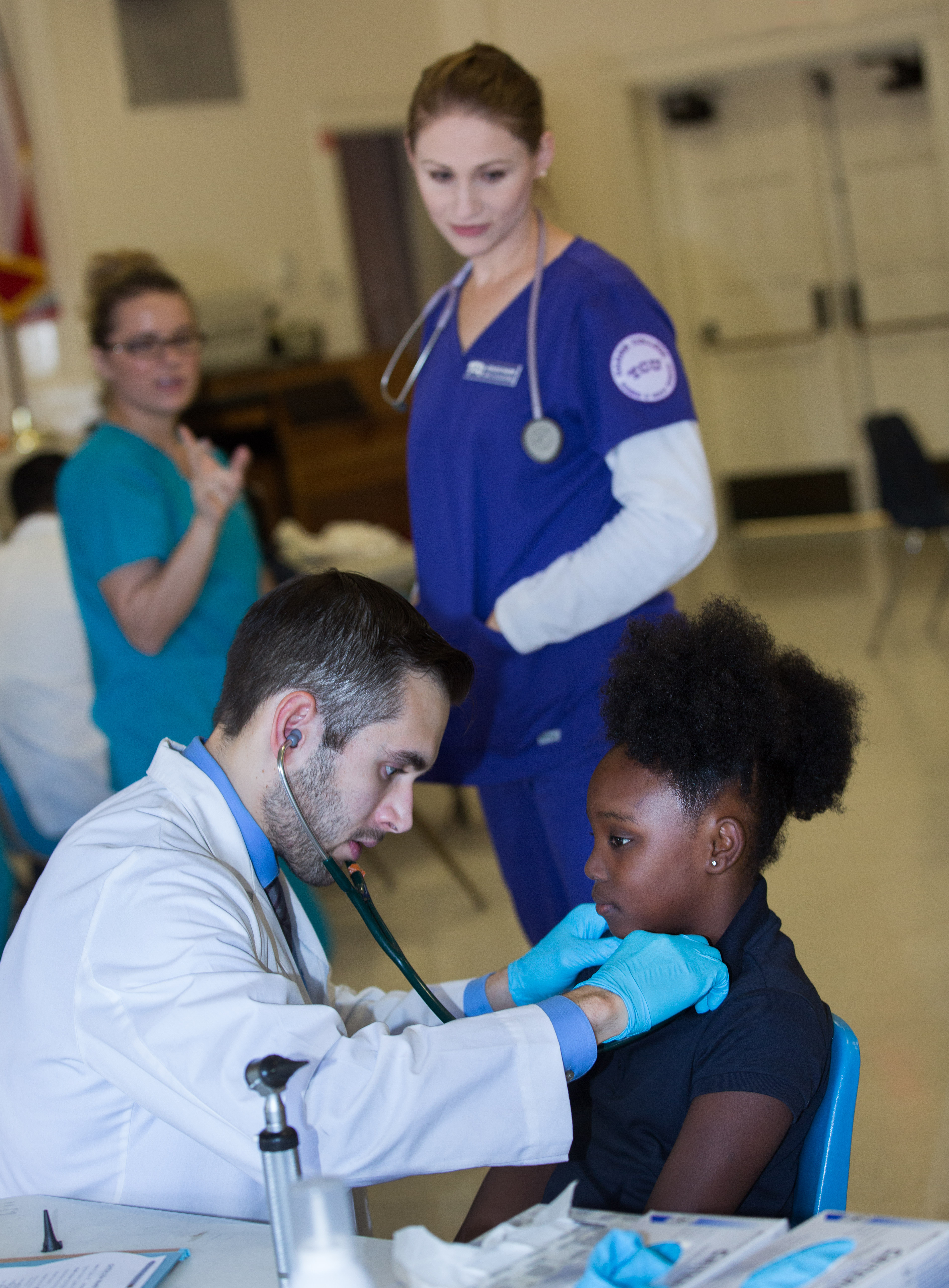 a doctor listens to the heartbeat of a little girl