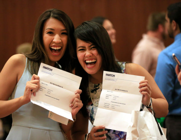 two TCOM students holding up their match letters