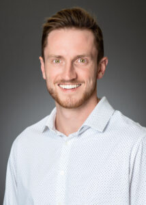 Logan Emery headshot. He's wearing a white and blue shirt.