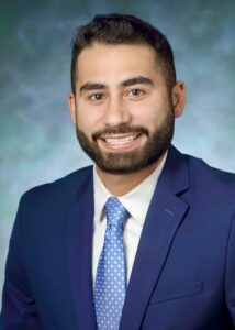 Randy Cornejo headshot. he is wearing a blue suit, white shirt and blue tie.