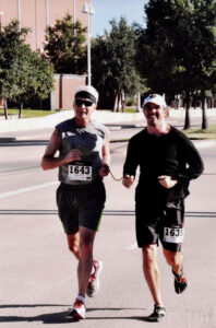 Reid Golden & Scott Hudson running together with Reid as Scott's guide. The two men are tethered together to make guiding easier.