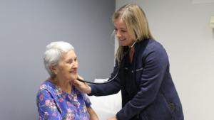 Cardiology PA Laine Markham takes the pulse of a patient and listens to her heartbeat