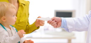 Pediatrician handing prescription to mom with baby in the foreground