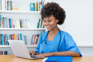 a woman with a stethoscope on working on a laptop